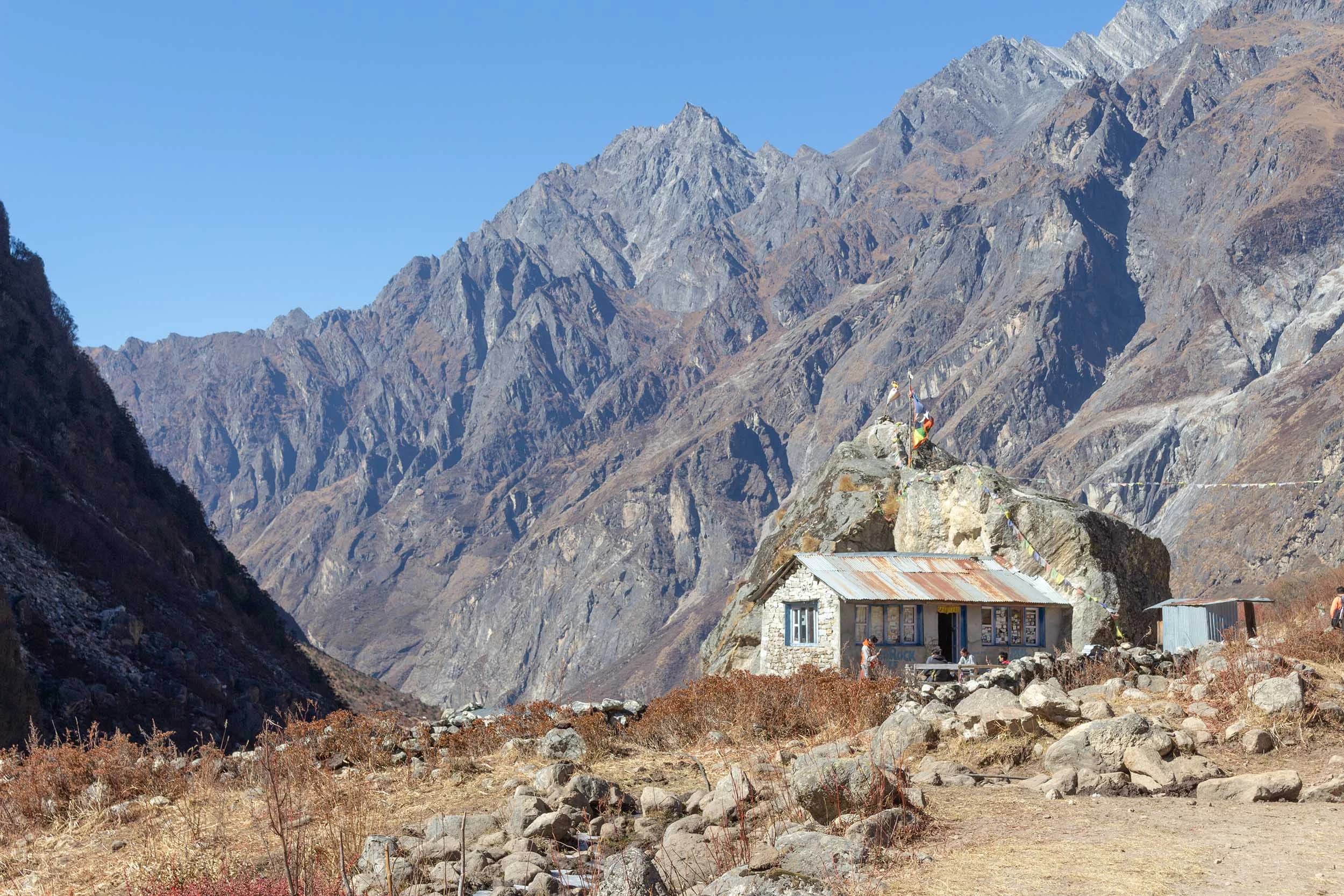 Vista della Valle di Langtang (Nepal) circondata da montagne. In primo piano c'è una piccola casa tradizionale