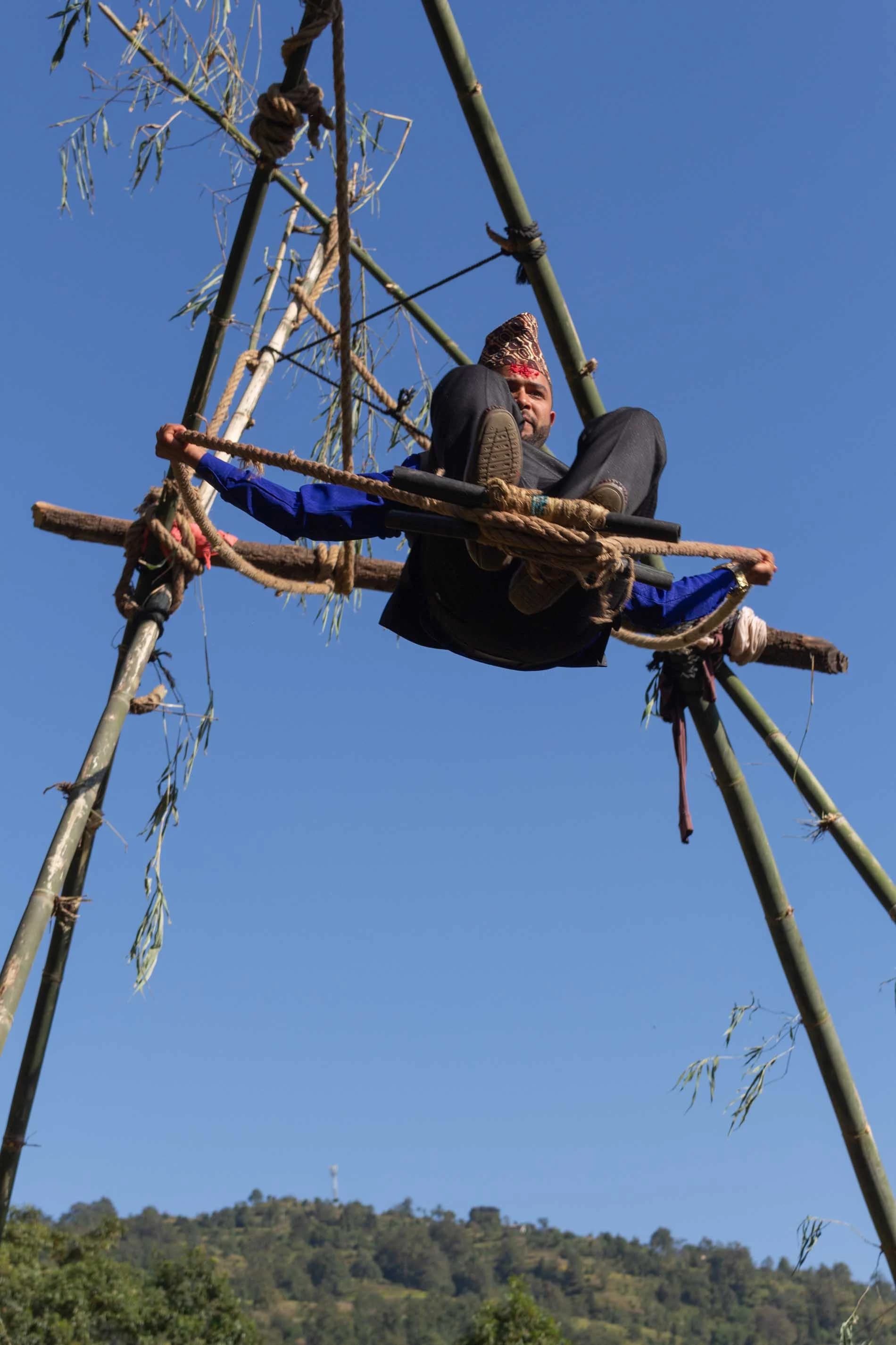 a Nepalese guy is having fun on a handmade wooden swing