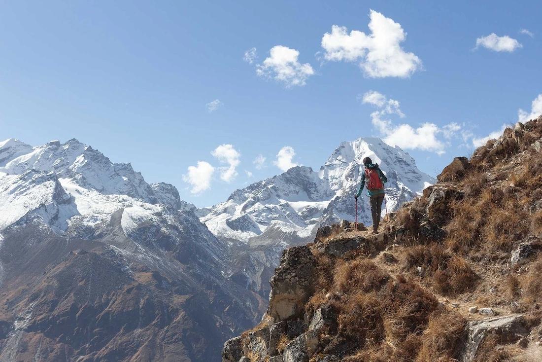 Trekker sul sentiero ripido con montagne innevate nello sfondo