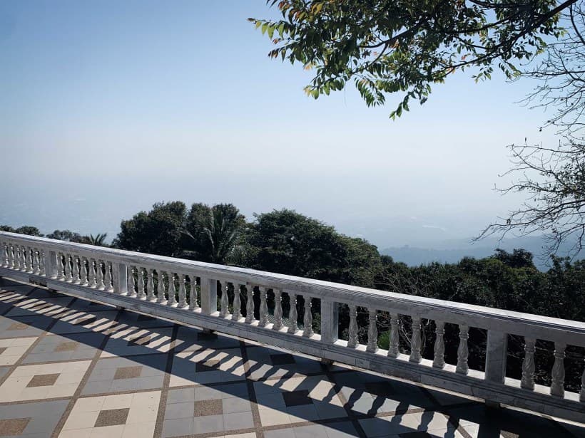 Smoke seen from Doi Suthep's viewpoint A terrace with a stone wall looking out onto trees and thick fog in the valley below