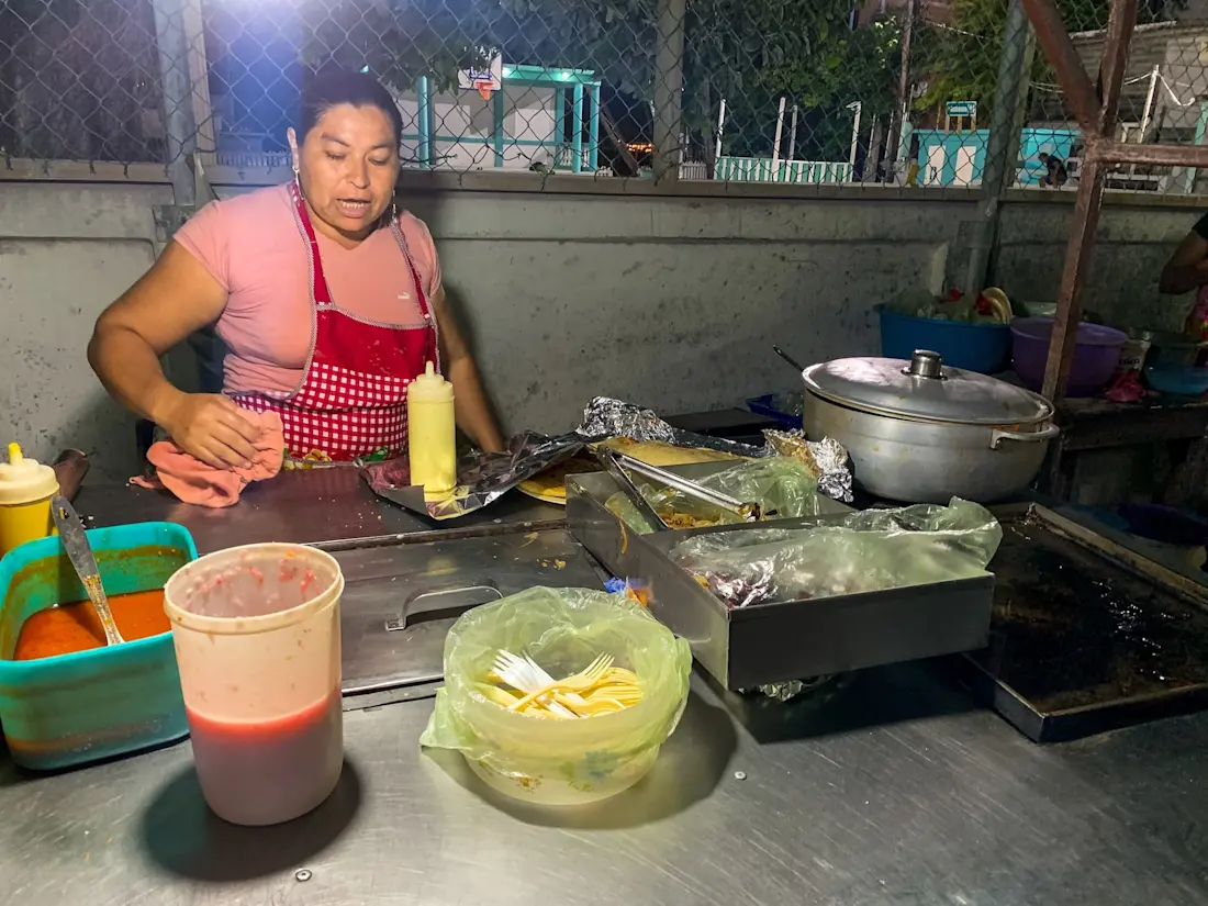 Le migliori pupusas e quesadillas a Caye Caulker Signora con il grembiule che sistema il piano della cucina in una bancarella di street food