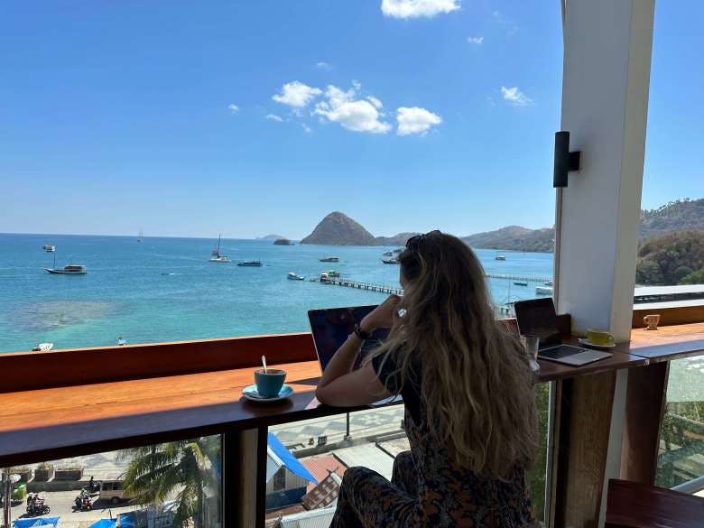 Bea working in a cafe in front of the sea in Labuan Bajo, Flores Island, Indonesia